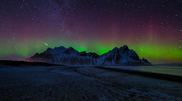 Aurora borealis over snow-capped mountains and starry sky. Vestrahorn, Iceland. Photo by Jonny Gios