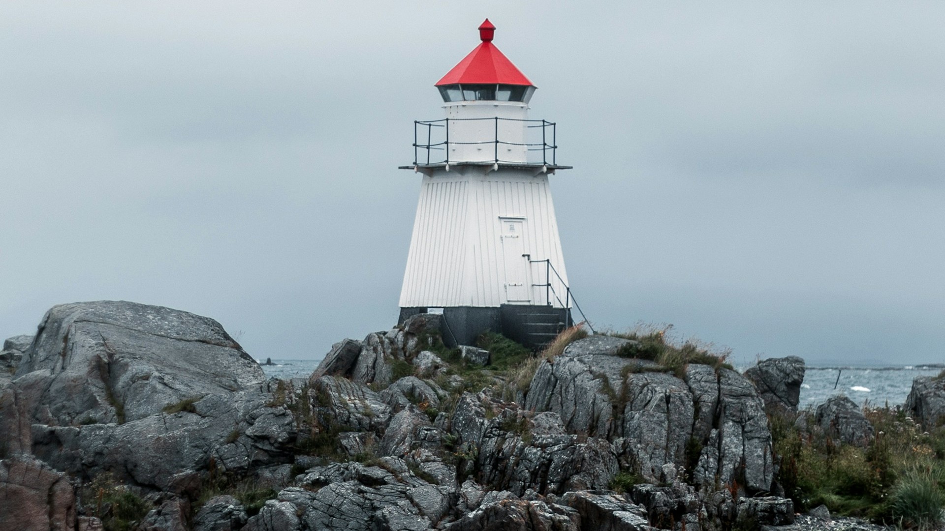 A white lighthouse on a rocky coast. Photo by Jamo Images